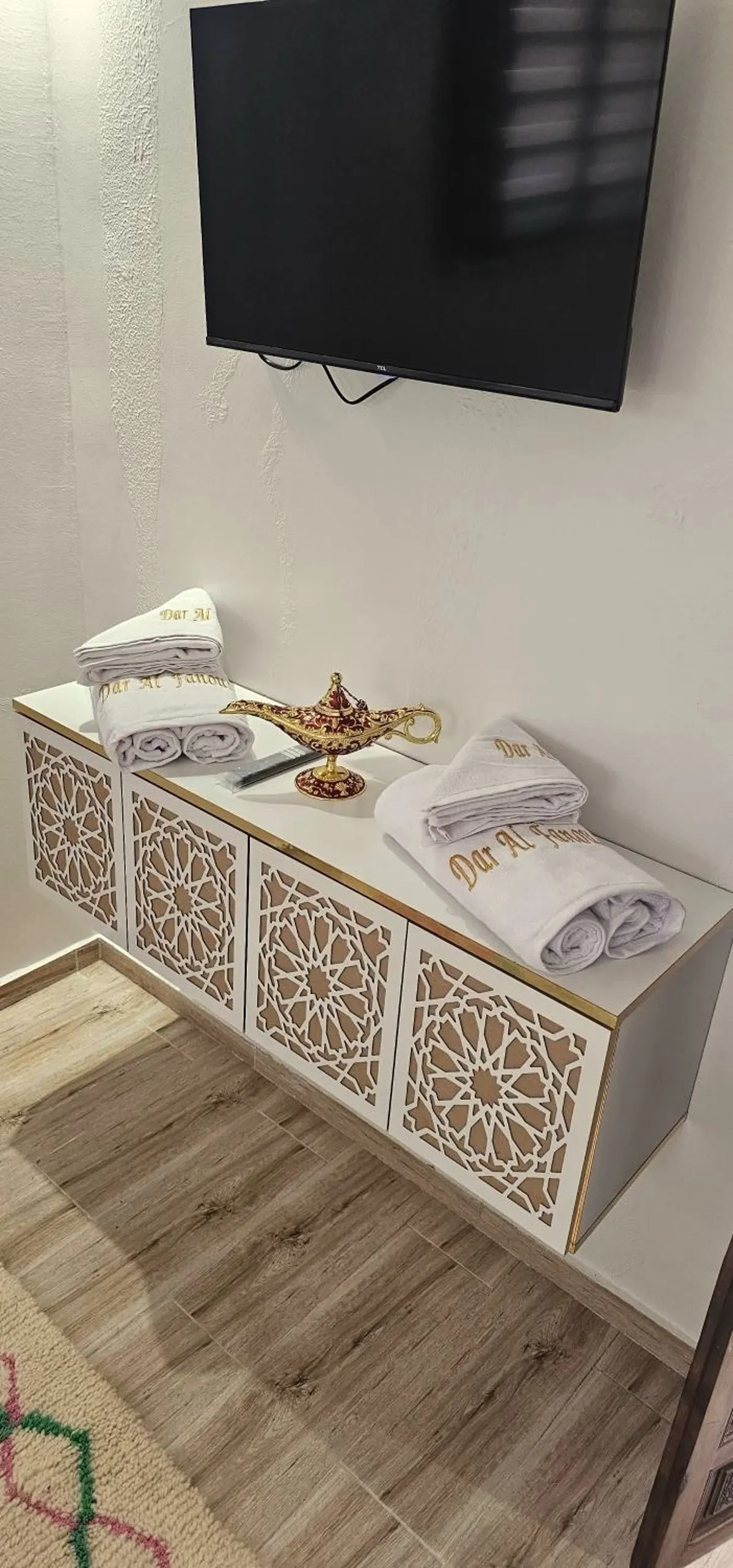 Console blanche ajourée, serviettes, lampe de laiton et télévision