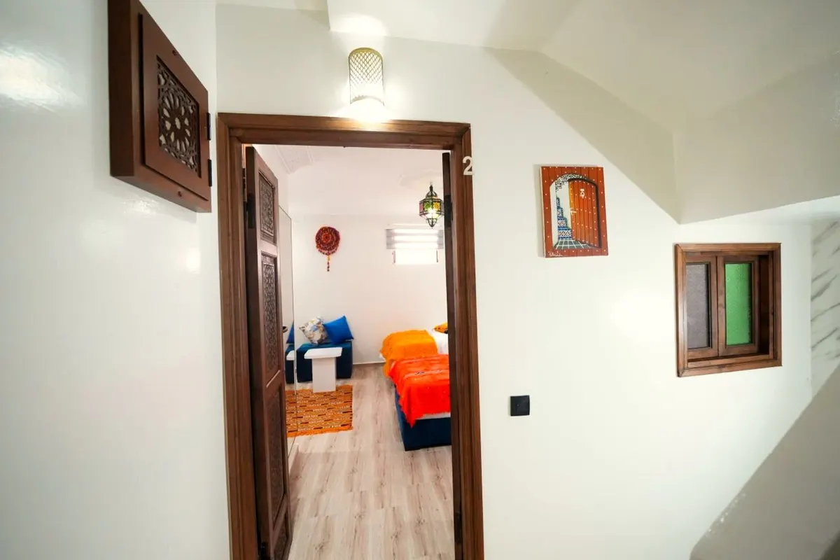 Palier : porte sculptée ouverte sur une chambre aux couvertures orange et bleues