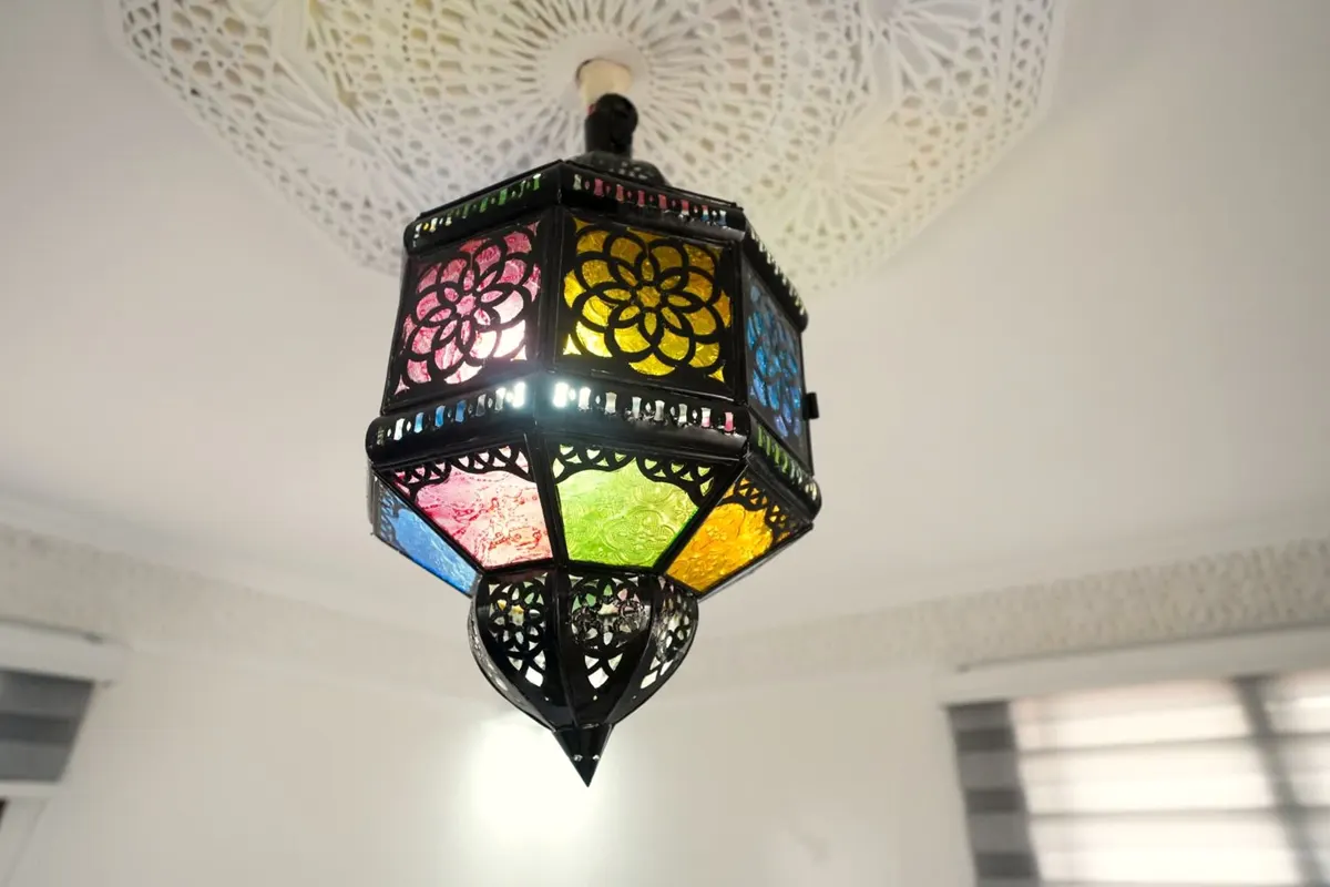 The stained-glass lantern hanging from a carved-plaster ceiling rose