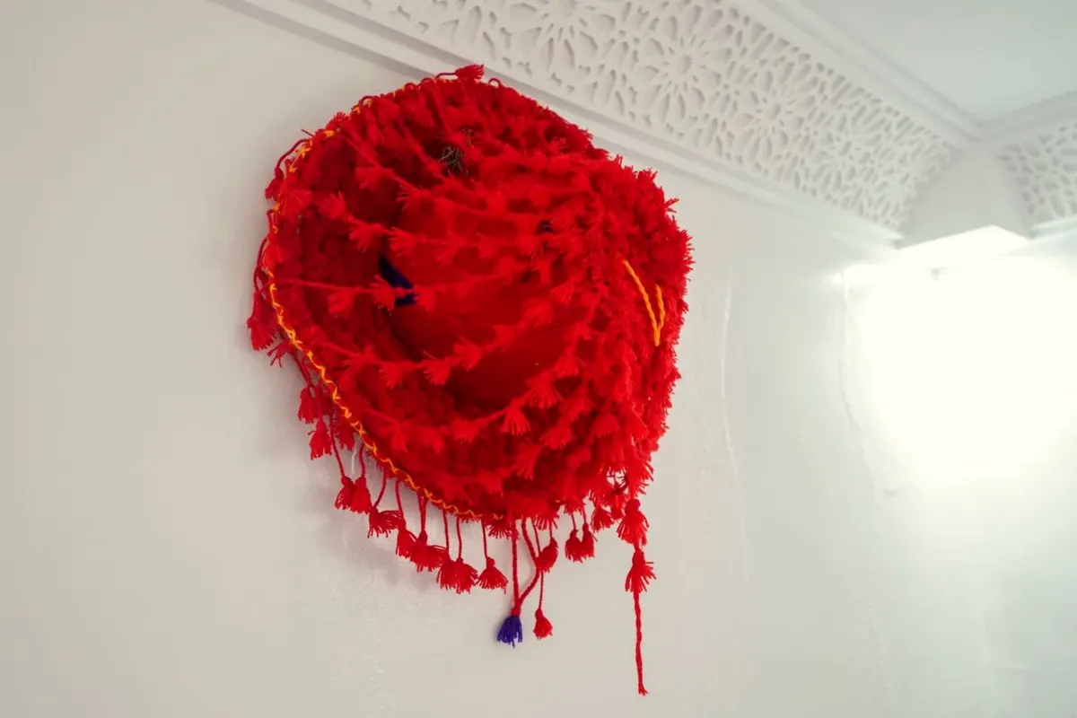 Pompon de laine rouge sous une corniche de plâtre sculpté