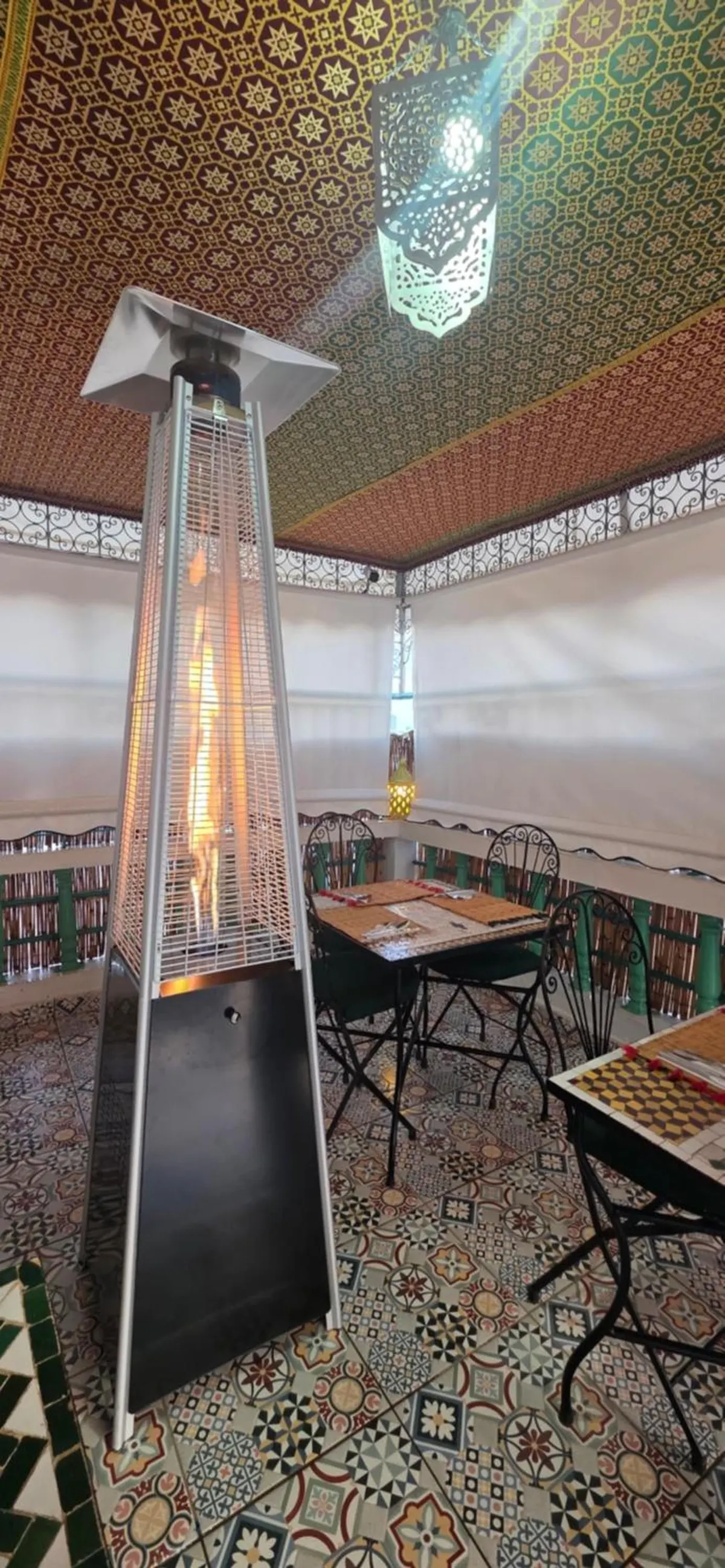 The terrace at night: patio heater, lit lantern, mosaic tables