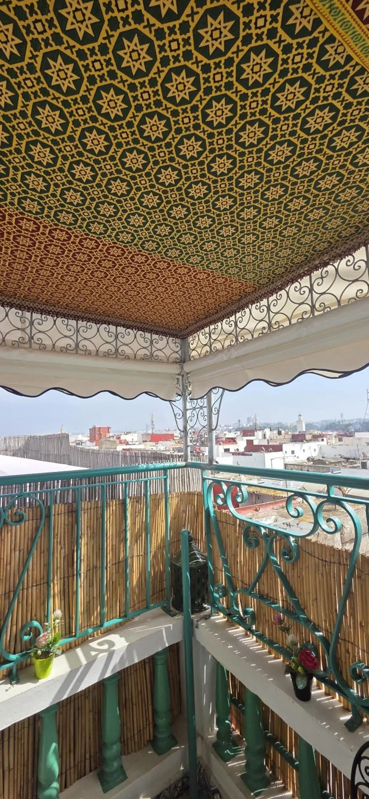 Edge of the terrace: painted ceiling, green iron balustrade and reed screens