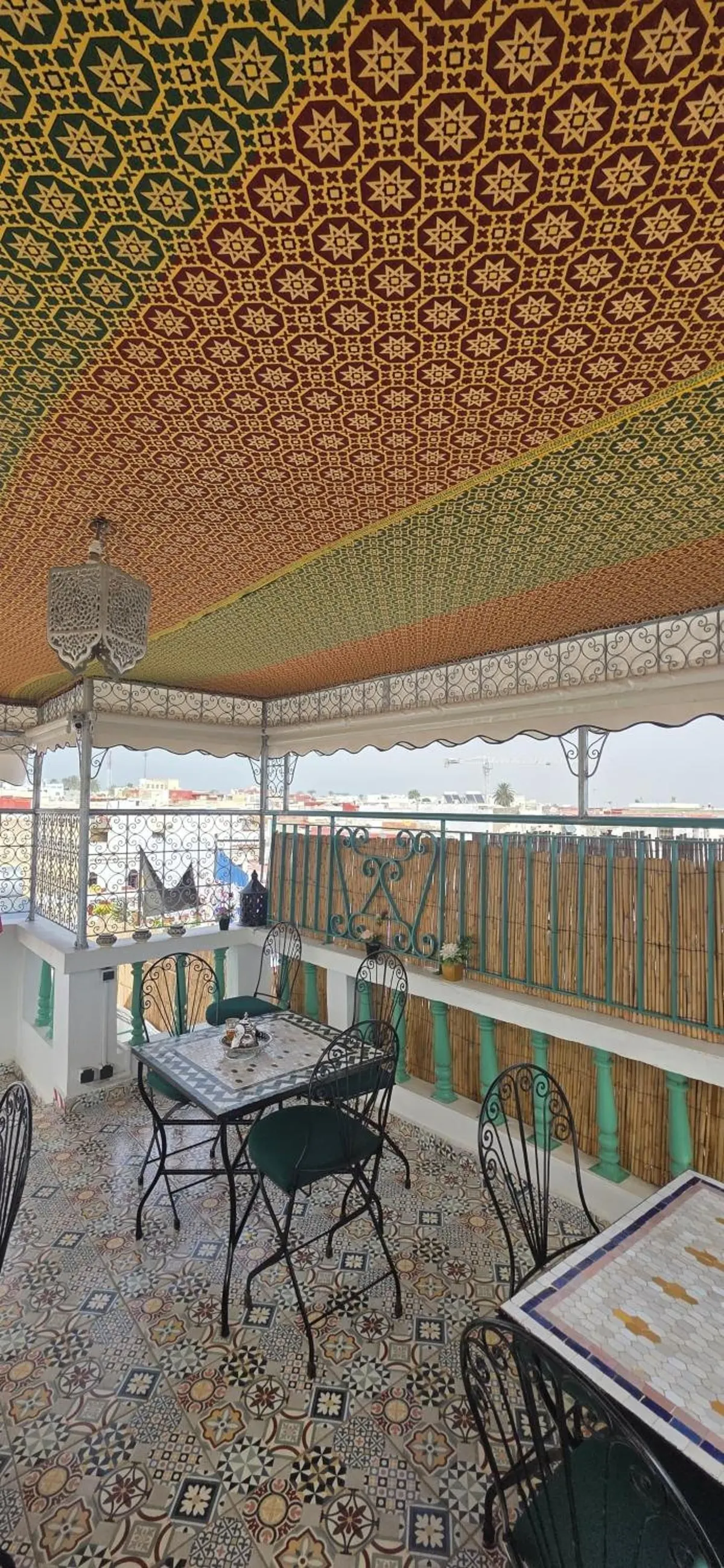 La terrasse sous le plafond peint, tables en mosaïque et ferronneries vertes