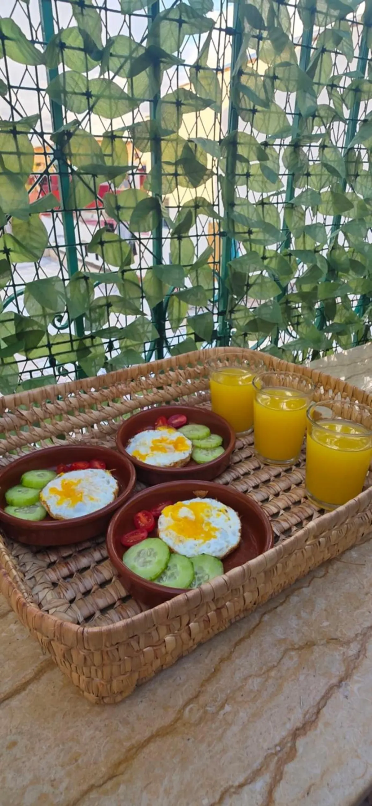 Breakfast tray on the roof: fried eggs with cucumber and three glasses of orange juice