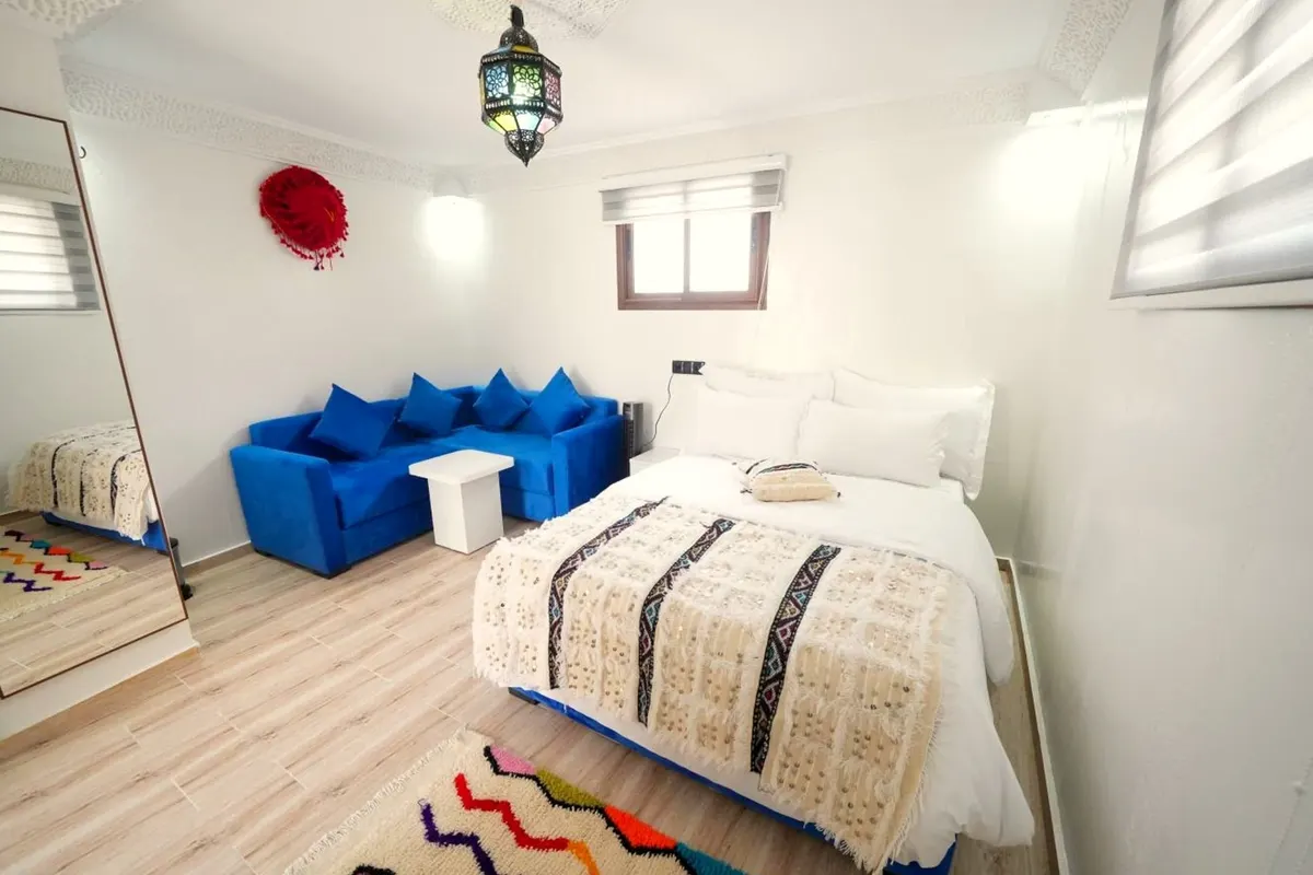 Double room: double bed with a cream-and-black handira, cobalt banquette, zigzag rug and lantern