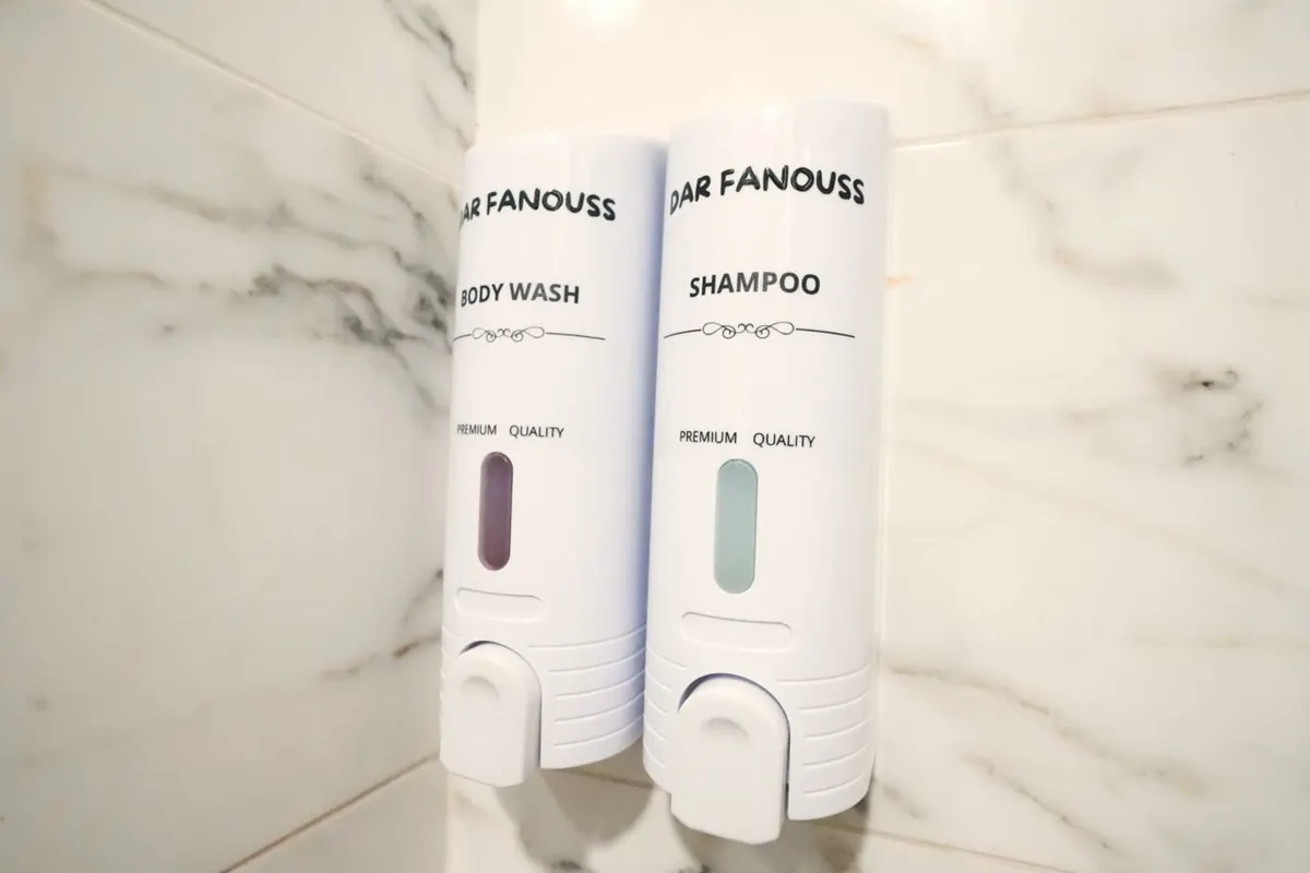 “Dar Fanouss” body wash and shampoo dispensers on marble-effect tiles