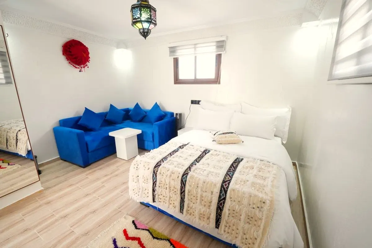 Double room: double bed with a cream-and-black handira, cobalt banquette, zigzag rug and lantern
