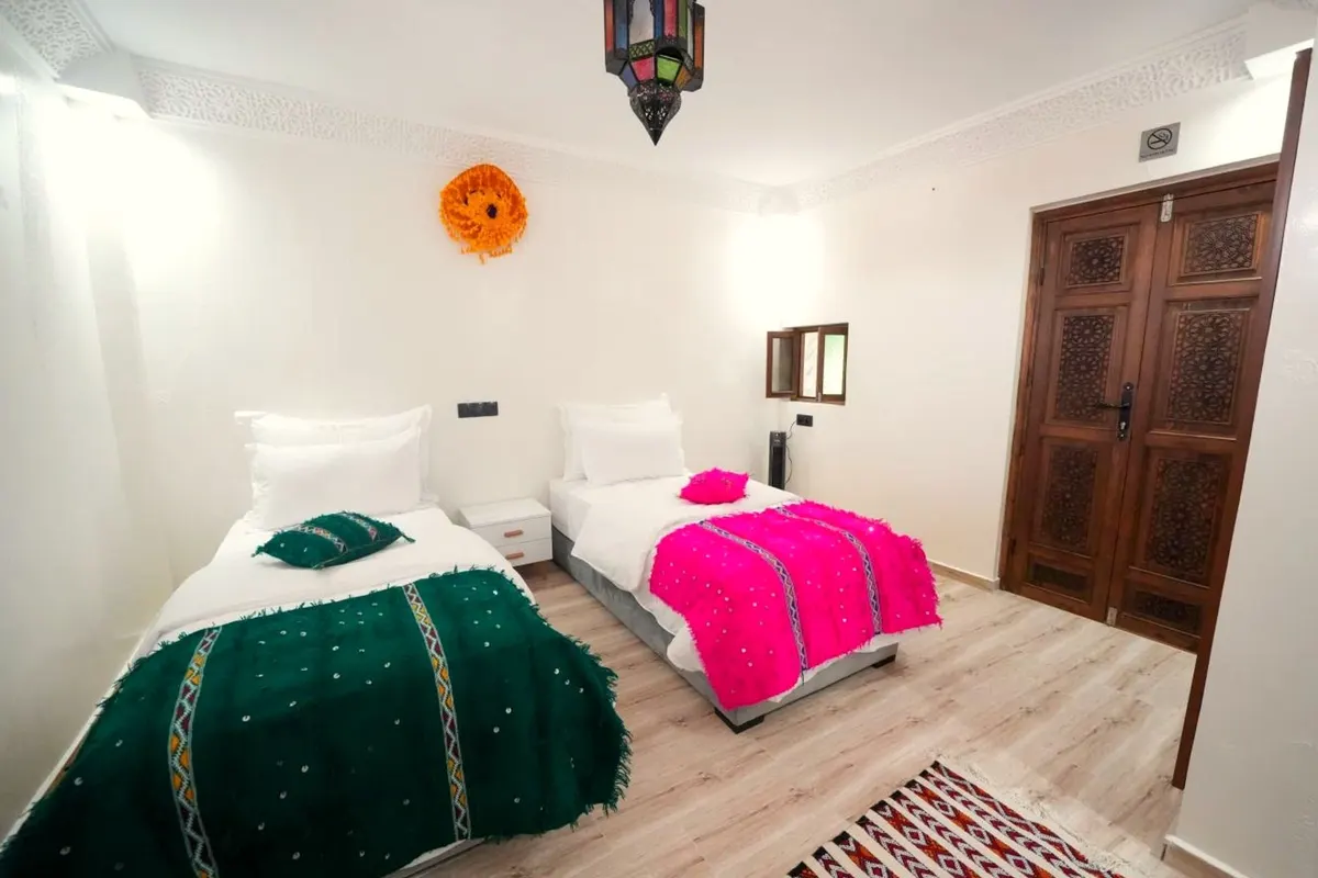 Emerald and fuchsia blankets on the two beds, carved wooden door