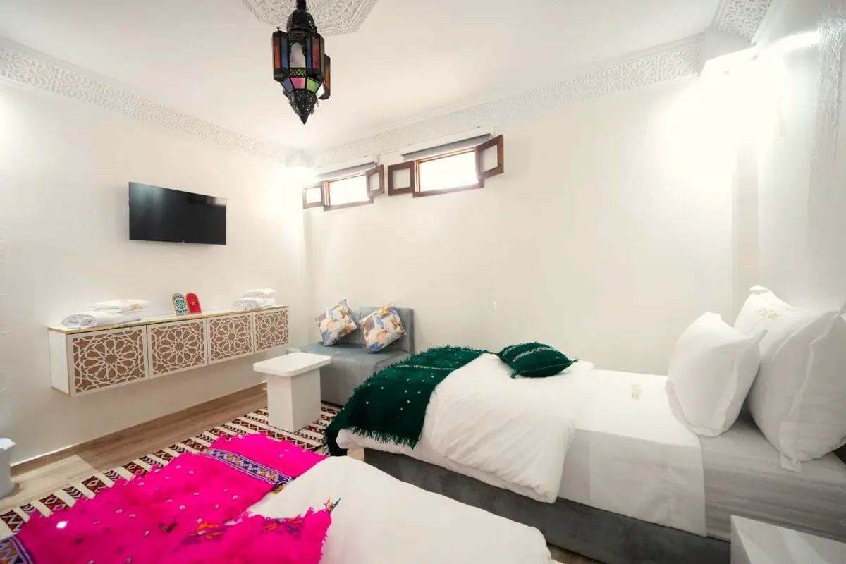 Twin beds with an emerald throw and a fuchsia rug, lantern overhead