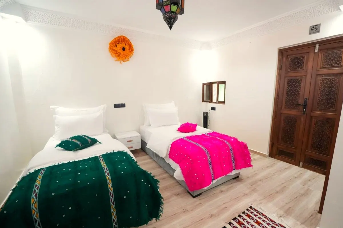 Emerald and fuchsia blankets on the two beds, carved wooden door
